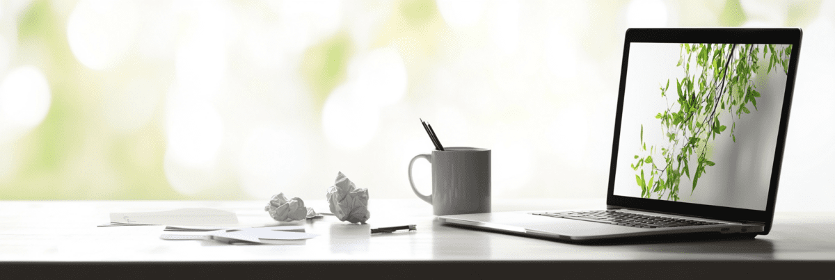 A workspace with a laptop, coffee mug, and crumpled paper—symbolizing the ups and downs of the creative process