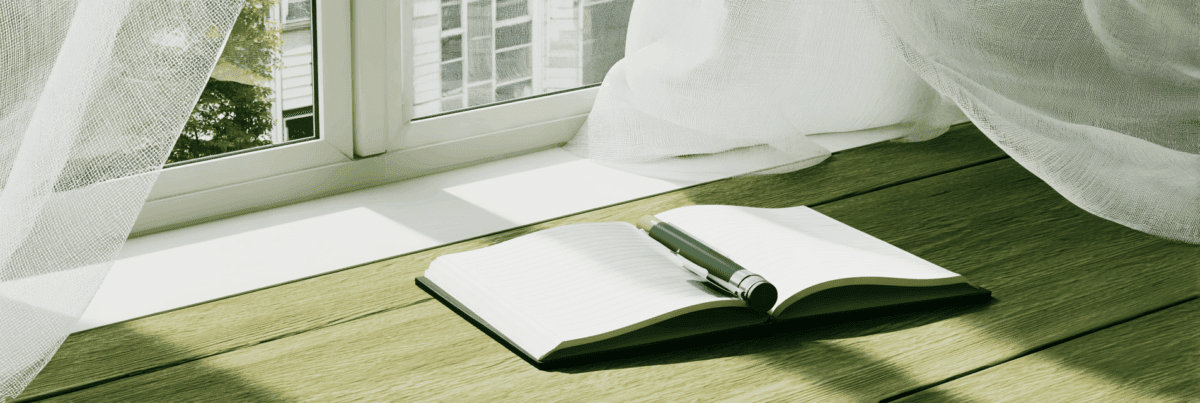 A sunlit window with sheer white curtains gently blowing inward. An open notebook with a pen rests on a wooden floor, bathed in soft afternoon light. The scene evokes peace, clarity, and quiet completion.