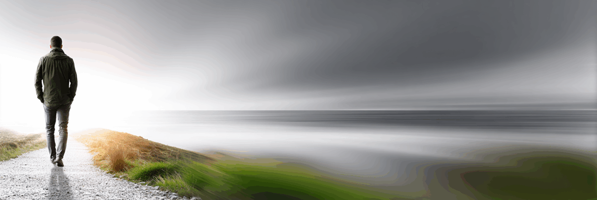 A person walks alone along a narrow coastal path, moving toward a bright horizon. The sky is gray and blurred with soft motion, and the ocean stretches out beside them. The scene feels quiet, open, and reflective.