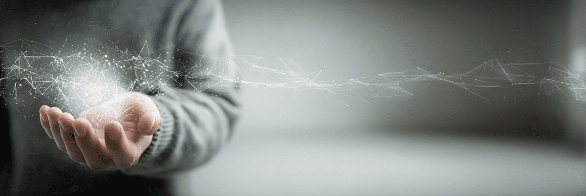 Close-up of an outstretched hand holding a glowing network of light particles and lines that extend outward and gradually dissolve into the background
