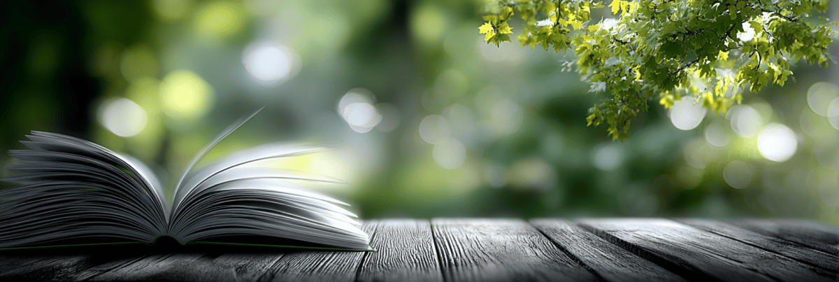 An open book rests on a weathered wooden table outdoors as a single page turns in a gentle breeze, symbolizing that one chapter is only part of a larger stor